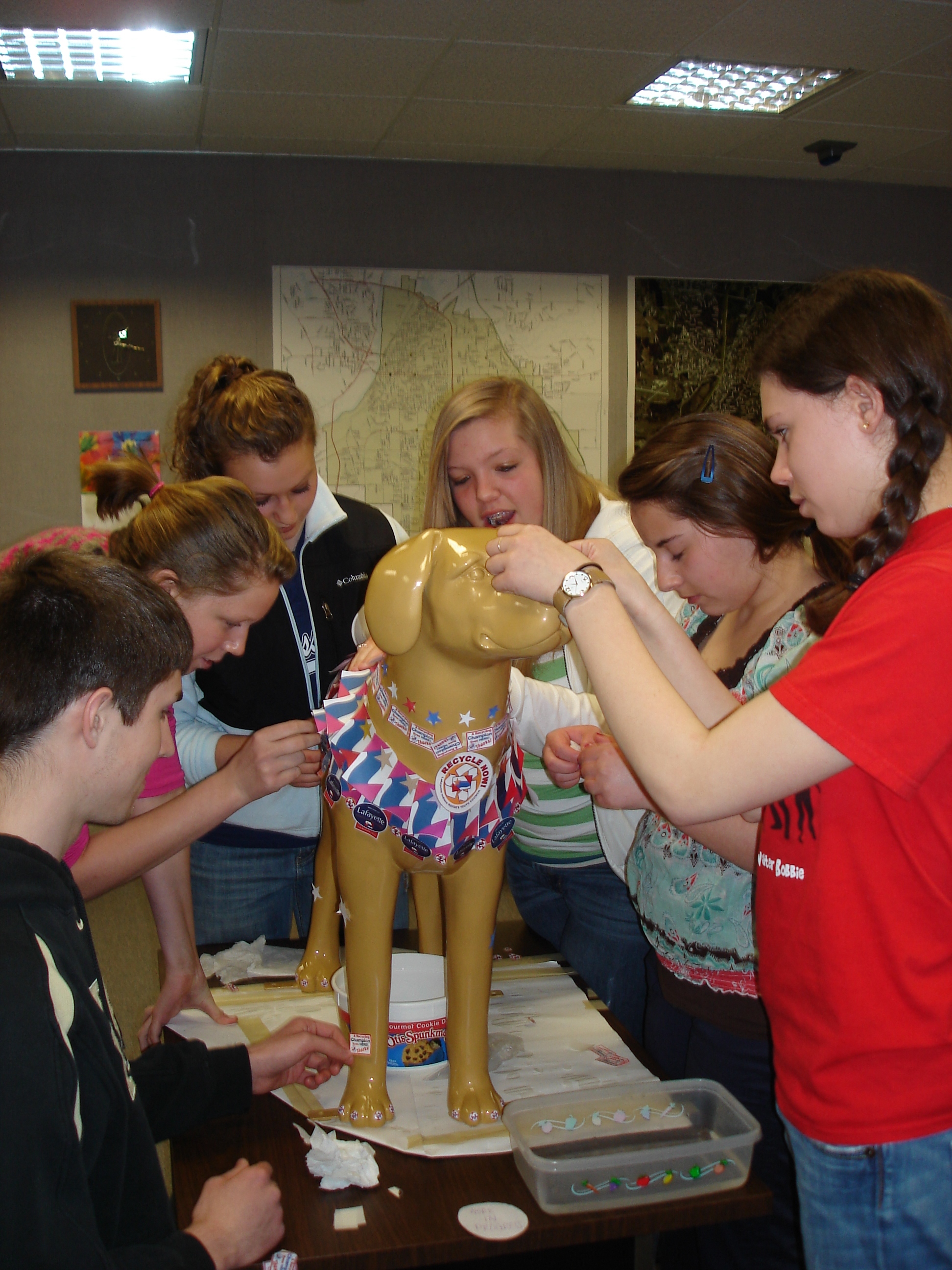Teenagers putting stickers onto a plastic dog